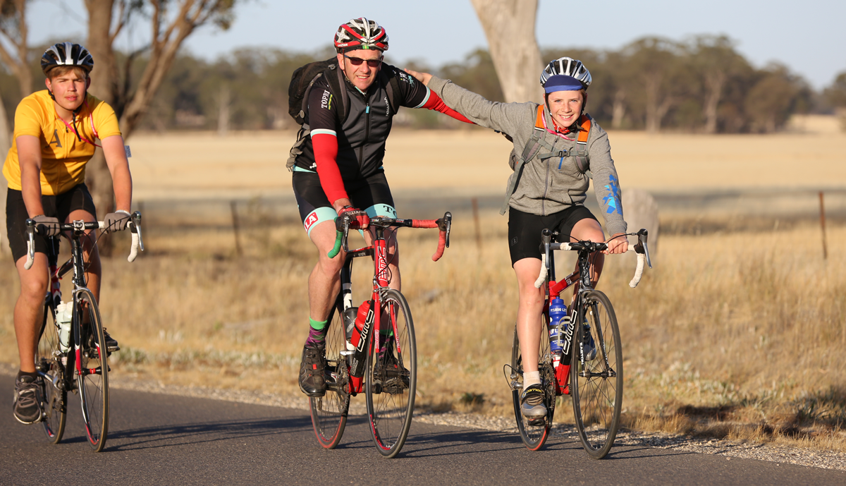 Three adult bicyclists riding through the woods